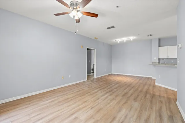 a view of empty room with wooden floor and fan
