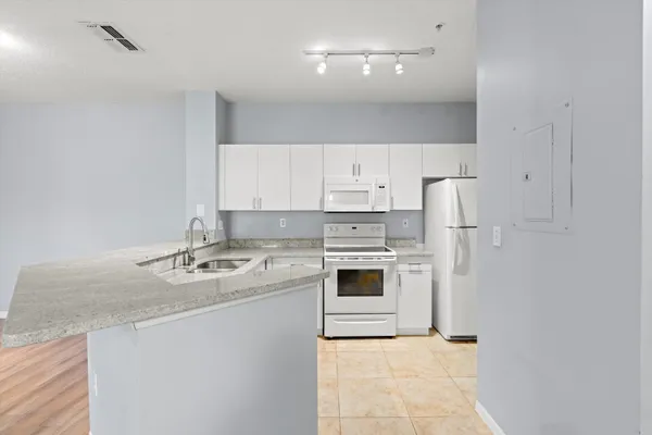 a kitchen with a sink a stove a refrigerator and white cabinets