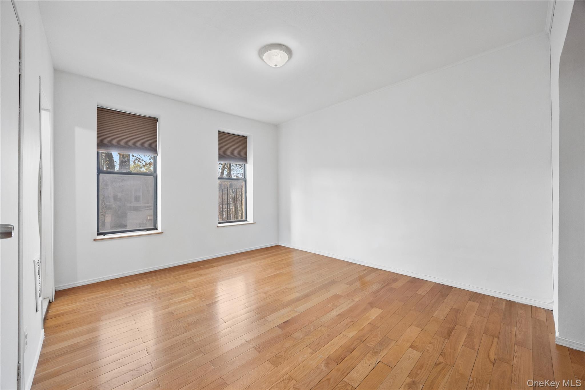 71-11 68th Street Queens, NY 11385 - Photo 5 of 24 Empty room with light wood-style floors and baseboards
