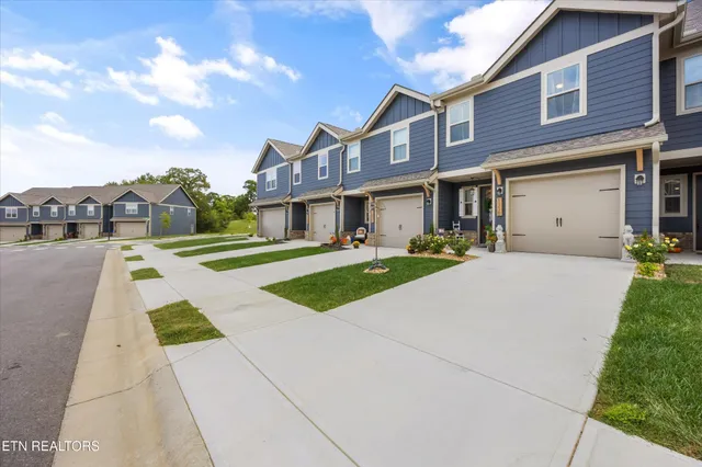 a front view of a building with garden and trees