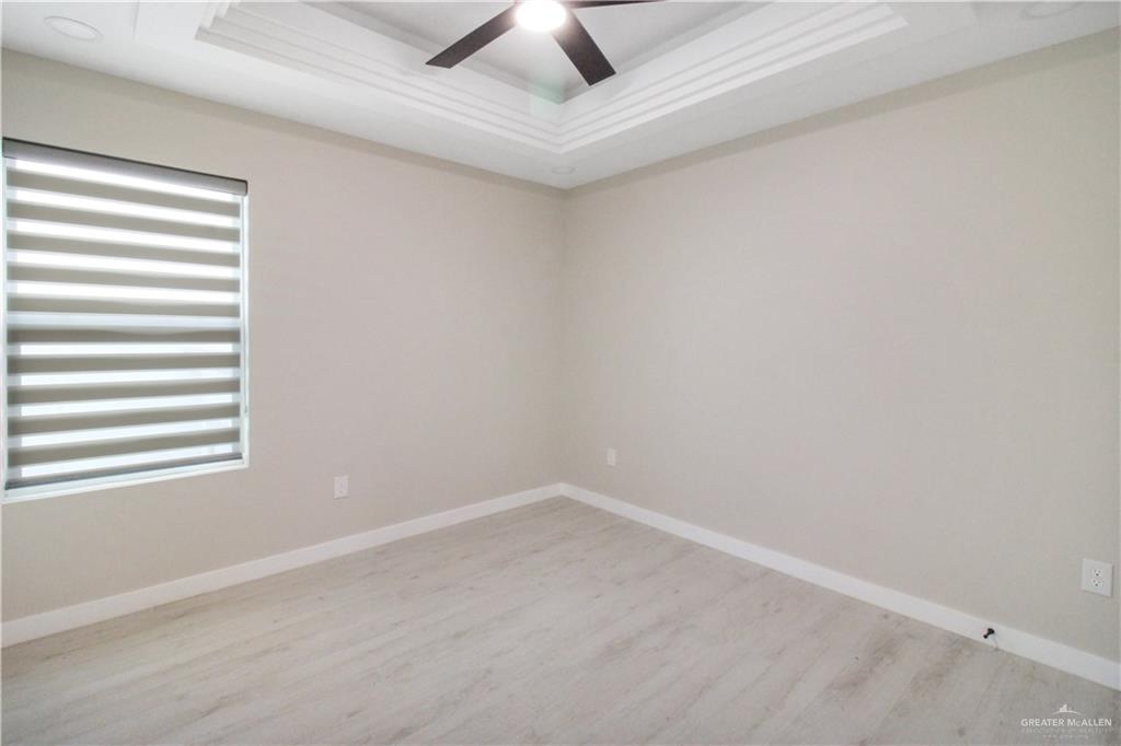 2202 Corales Street Mission, TX 78573 - Photo 12 of 18 Empty room with a tray ceiling, light wood finished floors, and a ceiling fan