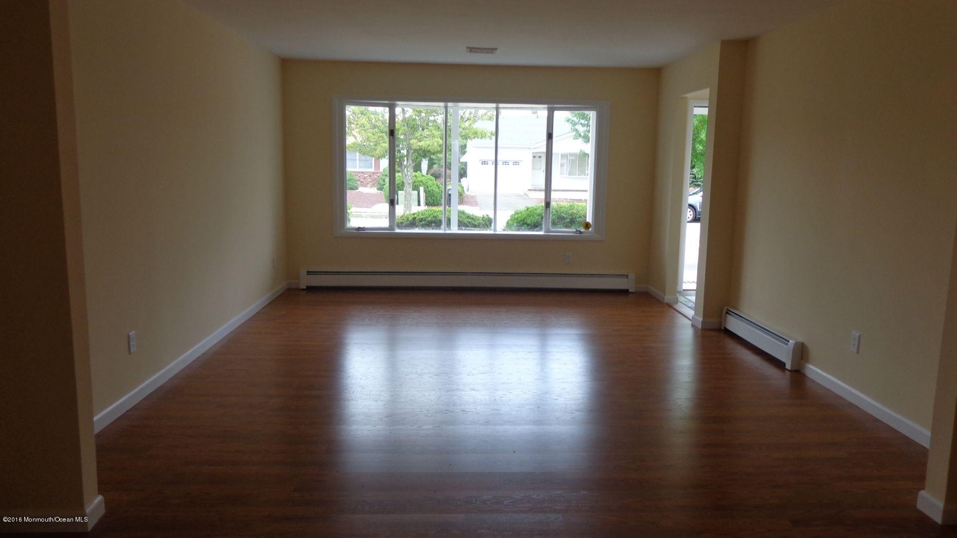 4 Garrett Road Toms River, NJ 08757 - Photo 4 of 19 an empty room with wooden floor and windows with curtains