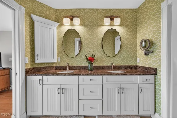 a bathroom with a granite countertop double vanity sink and a mirror