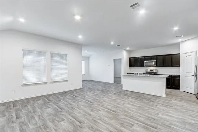 a large kitchen with stainless steel appliances kitchen island a large counter top and a stove top oven