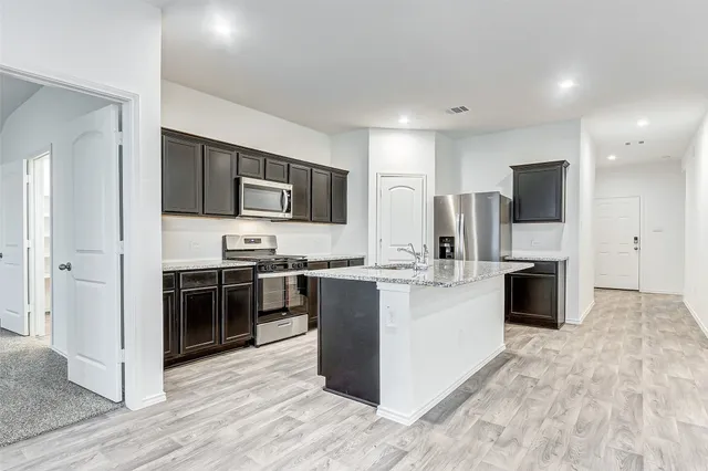 a large kitchen with stainless steel appliances granite countertop a stove and a refrigerator