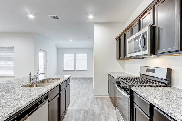 a kitchen with stainless steel appliances granite countertop a sink stove and cabinets