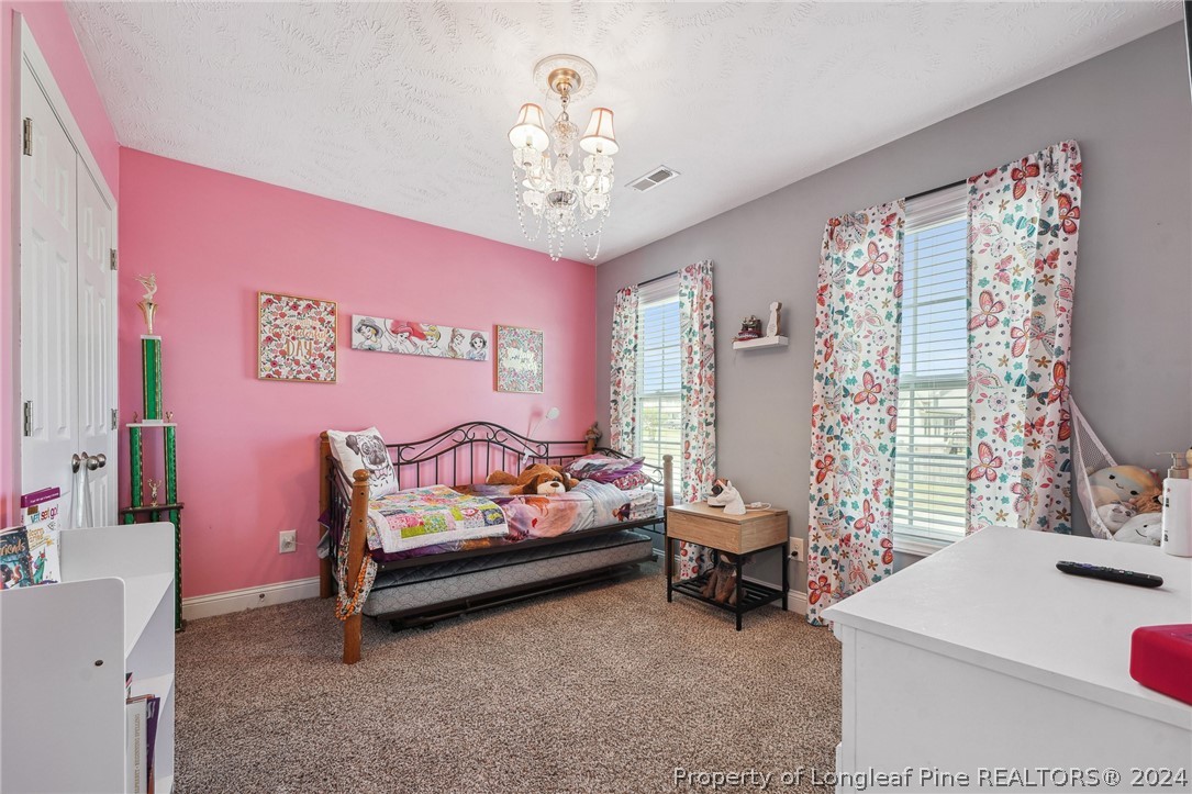 176 Vandercroft Way Bunnlevel, NC 28323 - Photo 23 of 36 a bedroom with a bed and a chandelier