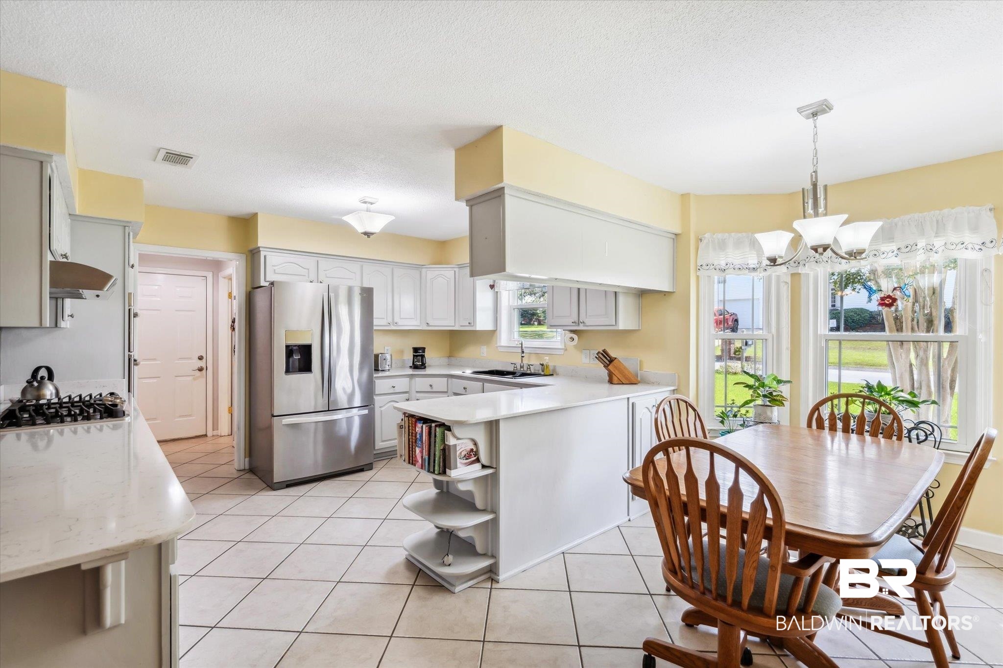 8710 Three Notch Road Mobile, AL 36619 - Photo 6 of 30 Kitchen with appliances with stainless steel finishes, a notable chandelier, light tile patterned floors, and wall chimney exhaust hood