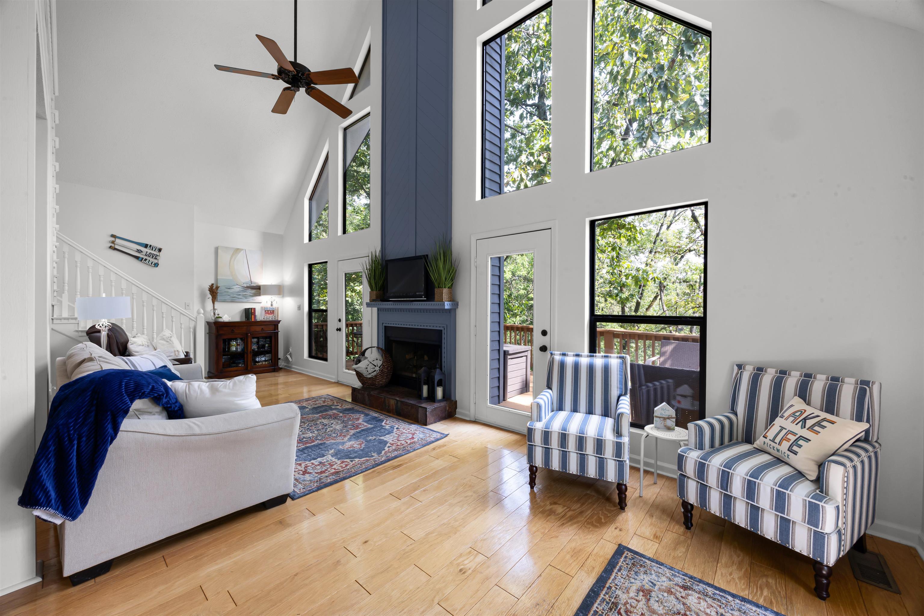 70 Point Clear Cove Savannah, TN 38372 - Photo 13 of 25 Living area featuring high vaulted ceiling, a ceiling fan, light wood-style floors, a fireplace, and stairs