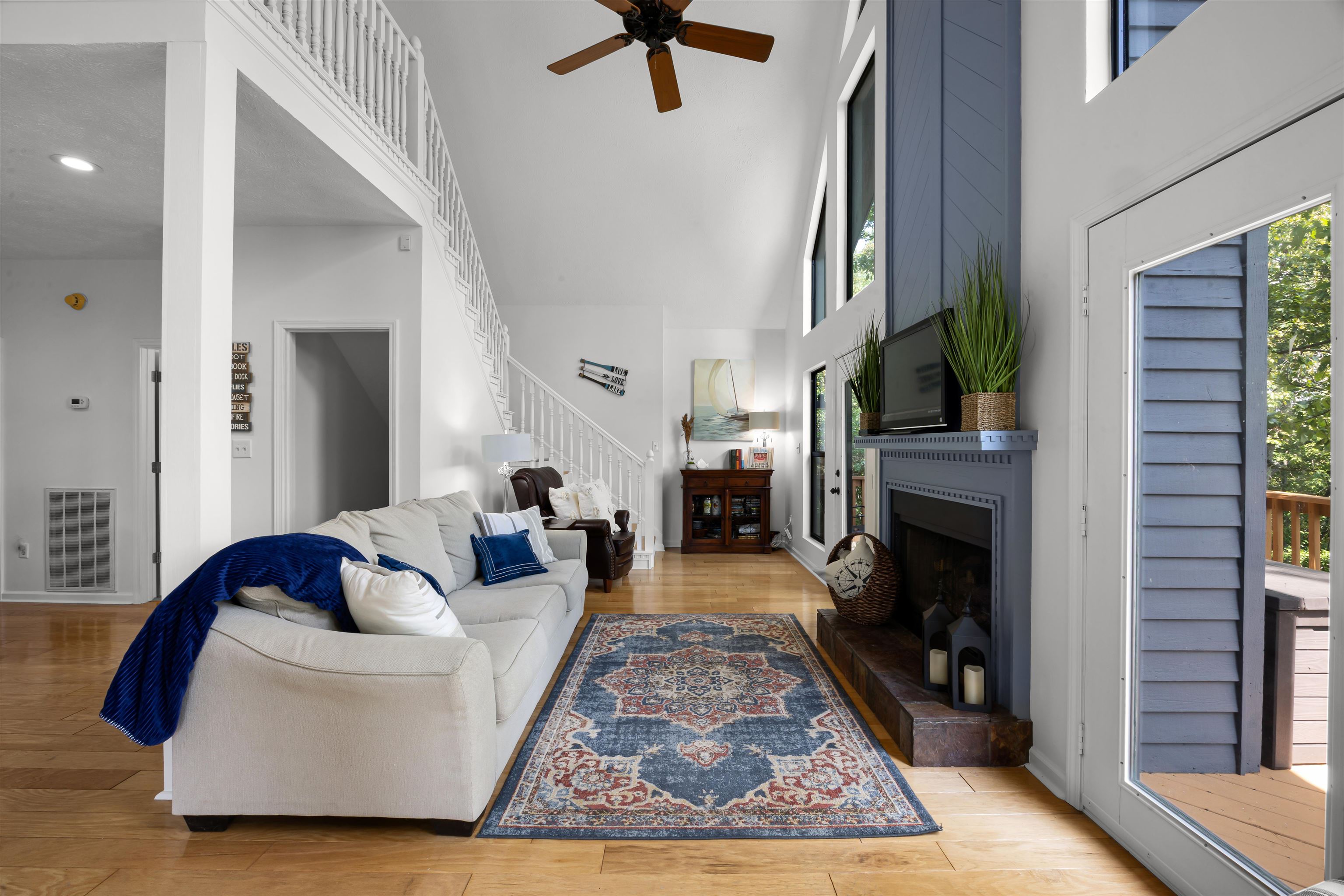 70 Point Clear Cove Savannah, TN 38372 - Photo 15 of 26 Living room featuring light wood finished floors, a large fireplace, a towering ceiling, stairway, and a ceiling fan