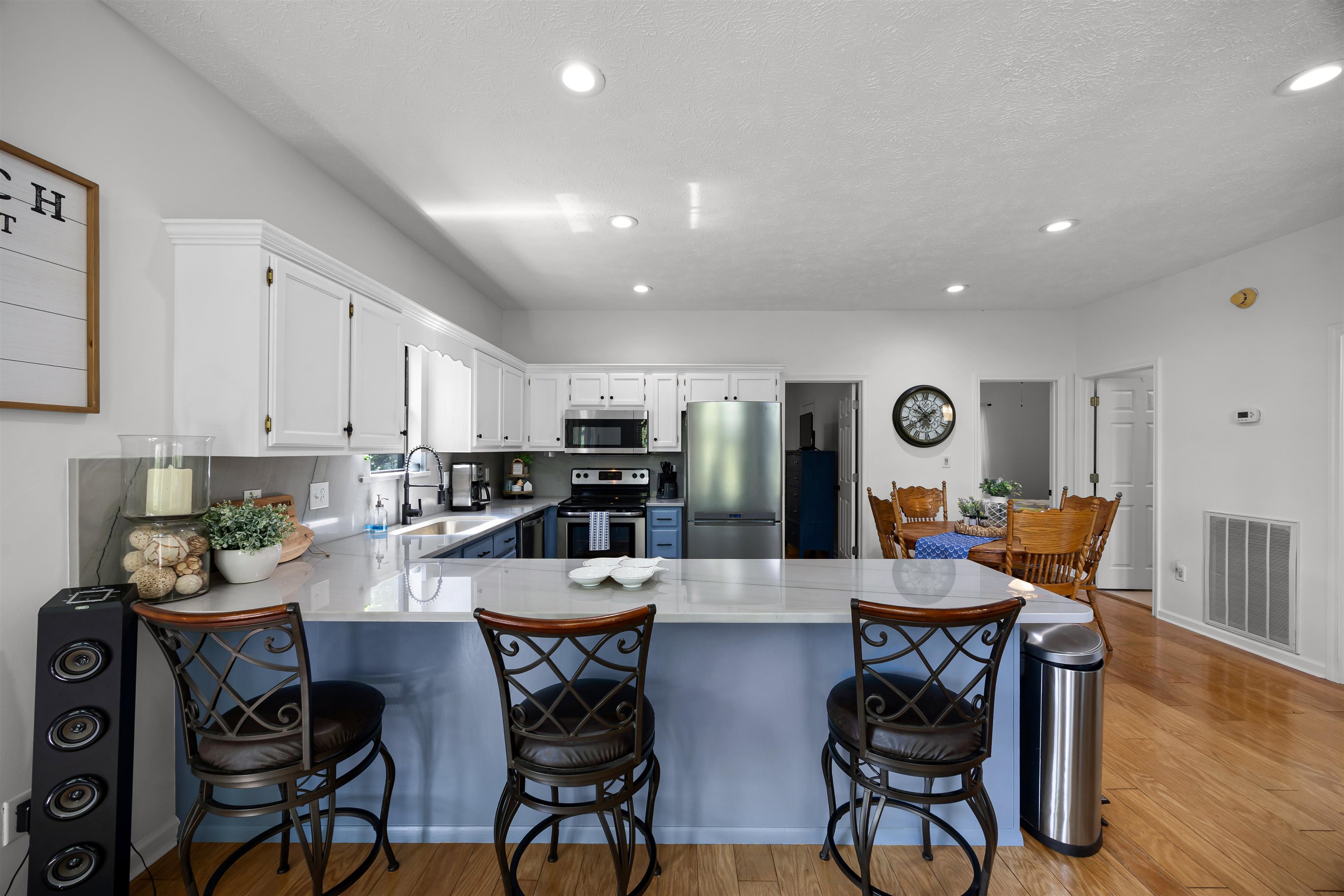 70 Point Clear Cove Savannah, TN 38372 - Photo 17 of 26 Kitchen with a peninsula, quartzite countertops, white upper and blue lower cabinetry, stainless steel appliances, and light wood-style flooring