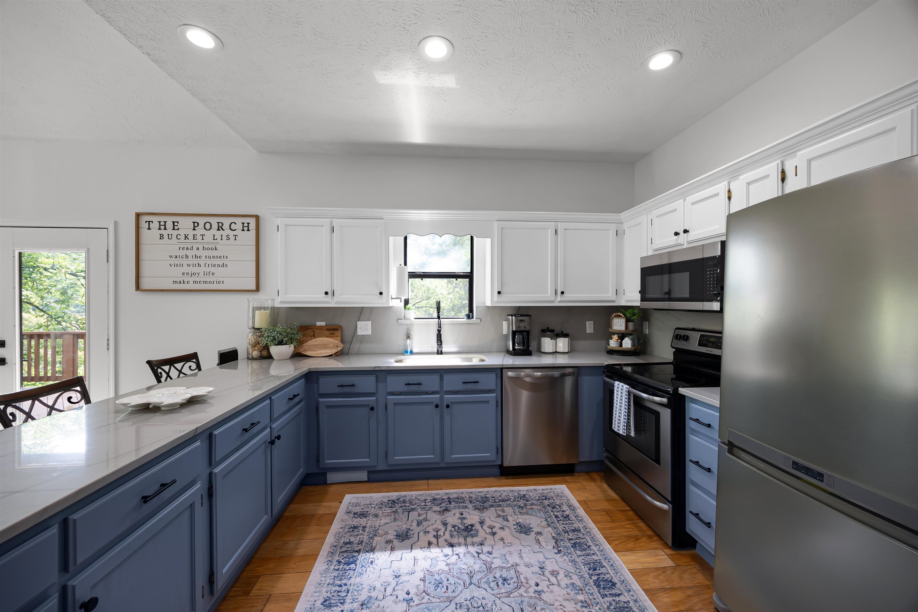 70 Point Clear Cove Savannah, TN 38372 - Photo 19 of 26 Kitchen featuring white upper and blue lower cabinetry, quartzite countertops, stainless steel appliances, light wood-style floors, and a textured ceiling
