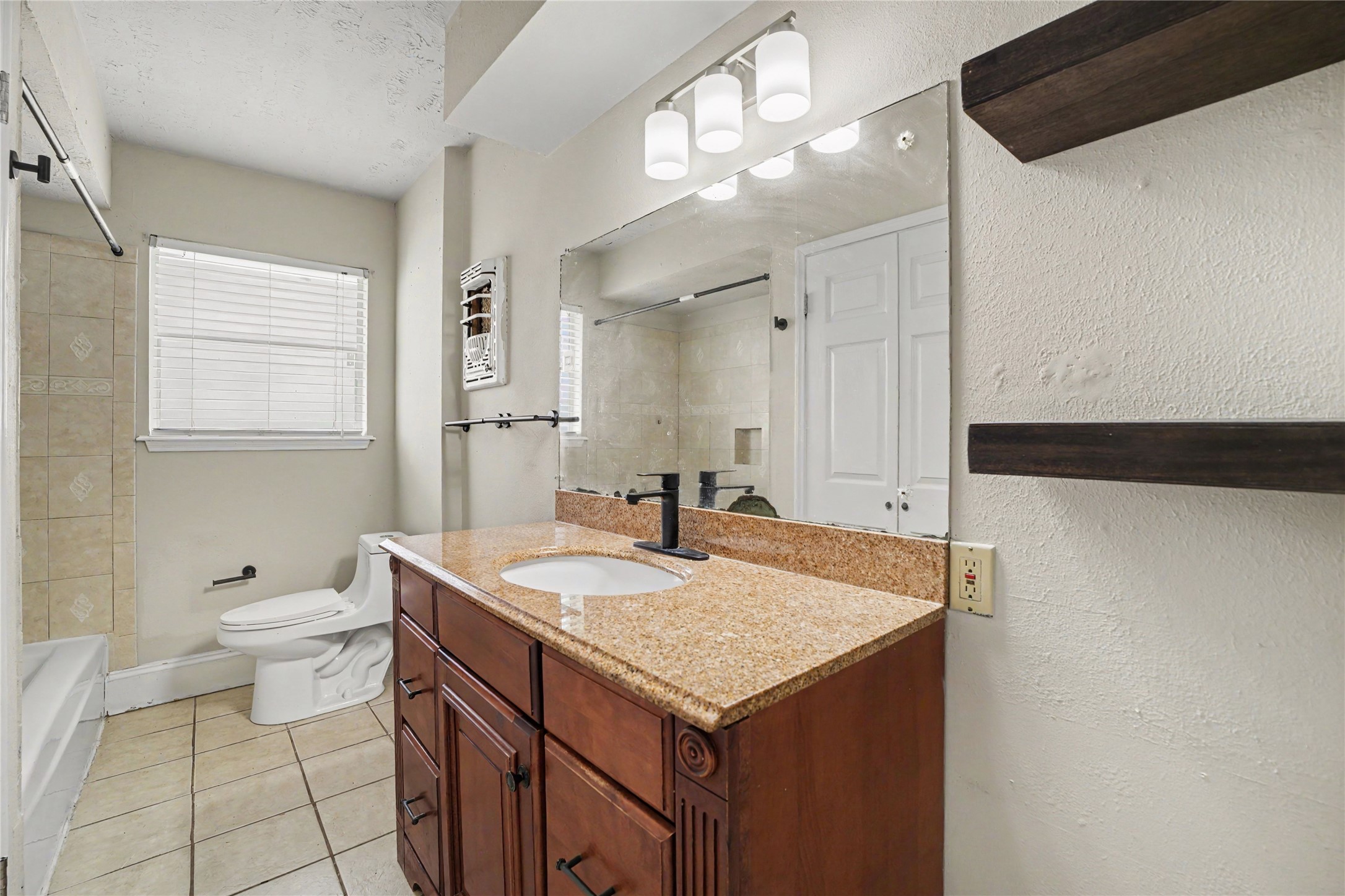8330 Springtime Lane Houston, TX 77075 - Photo 17 of 27 Second bathroom featuring a granite countertop, rich wood cabinetry, and a well-lit vanity mirror, complemented by a tiled shower and large window providing natural light.