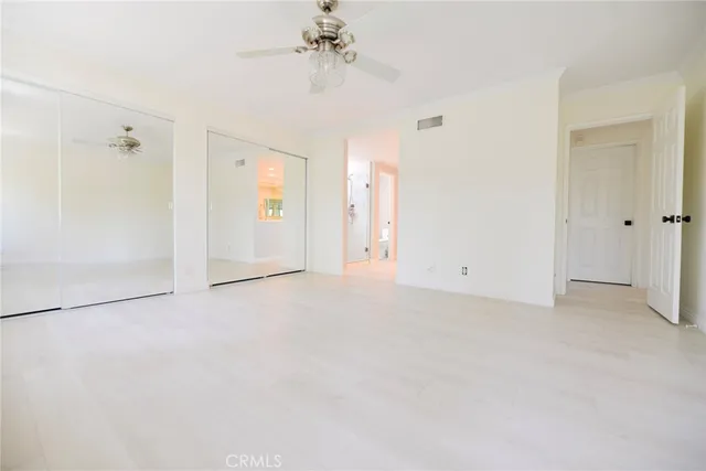 an empty room with chandelier fan and windows