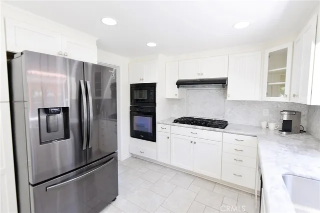 a kitchen with stainless steel appliances granite countertop a refrigerator a sink a stove and white cabinets