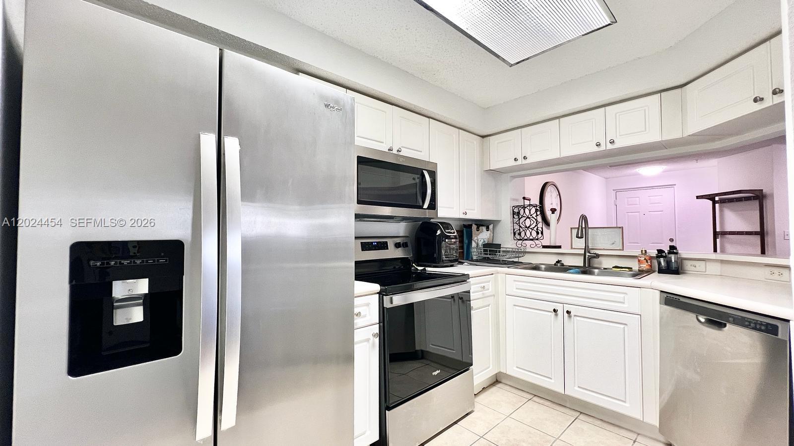 2727 Anzio Court, Unit 106 Palm Beach Gardens, FL 33410 - Photo 9 of 43 a kitchen with a sink stainless steel appliances and cabinets