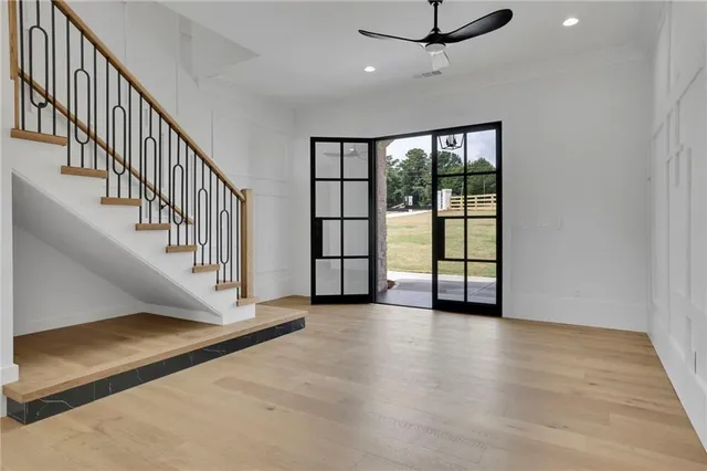 a view of an empty room with wooden floor and fan