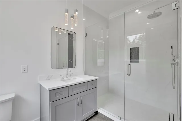 a bathroom with a granite countertop sink a toilet a mirror and shower