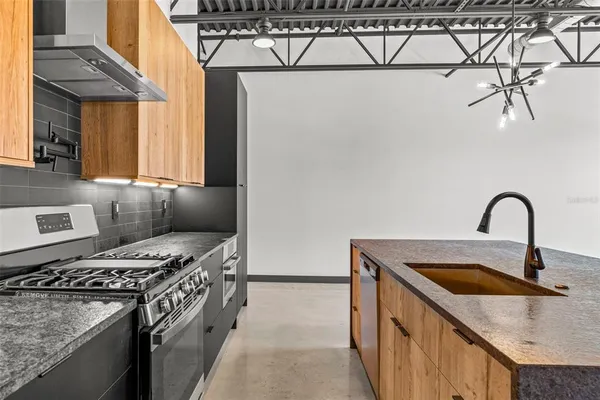 a kitchen with stainless steel appliances granite countertop a sink a stove and a refrigerator
