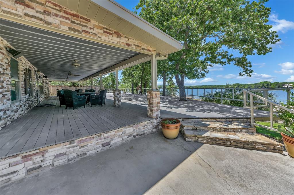 566 Selma Park Road Bowie, TX 76230 - Photo 21 of 40 Expansive covered patio featuring a planked deck surface, stone veneer accents, and ceiling fans