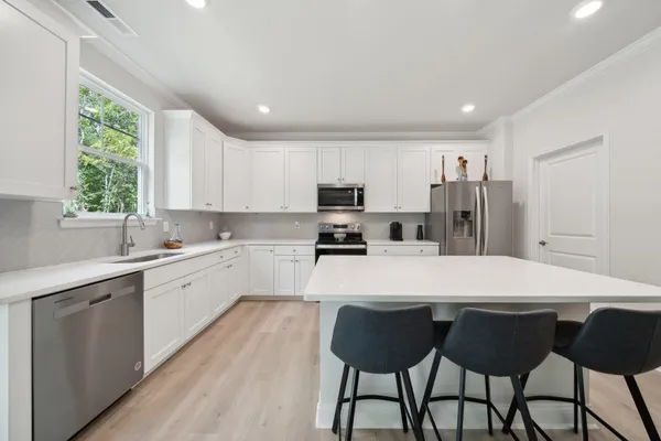a large kitchen with a table chairs refrigerator and microwave