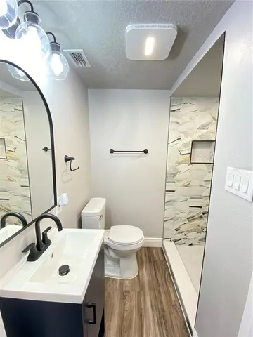 a bathroom with a sink a toilet a mirror and shower
