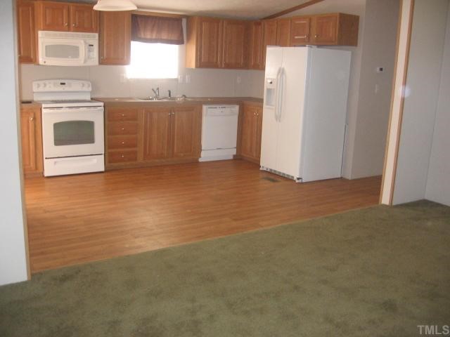 7621 Cassam Road Bahama, NC 27503 - Photo 4 of 8 a kitchen with granite countertop white cabinets and white appliances