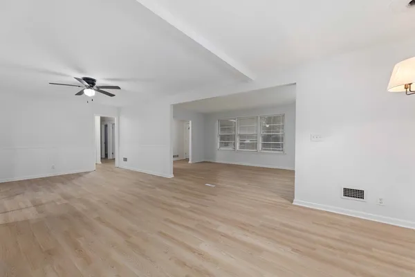 a view of an empty room with a window and wooden floor