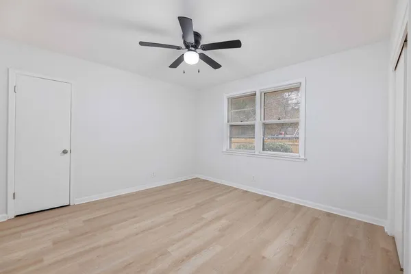 a view of empty room with wooden floor and ceiling fan
