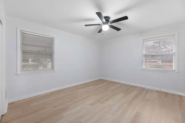 a view of a big room with wooden floor and windows