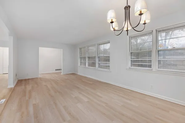 a view of an empty room with wooden floor and windows