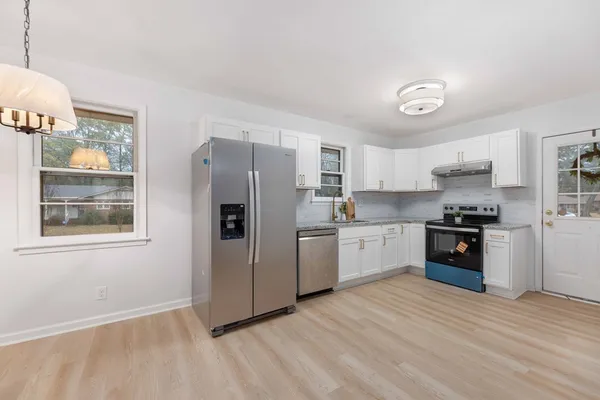a kitchen with granite countertop a refrigerator and a stove top oven