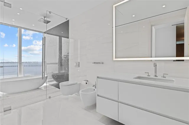 a bathroom with a granite countertop bathtub shower sink mirror and toilet