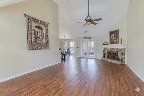 a view of a livingroom with a fireplace a ceiling fan and wooden floor