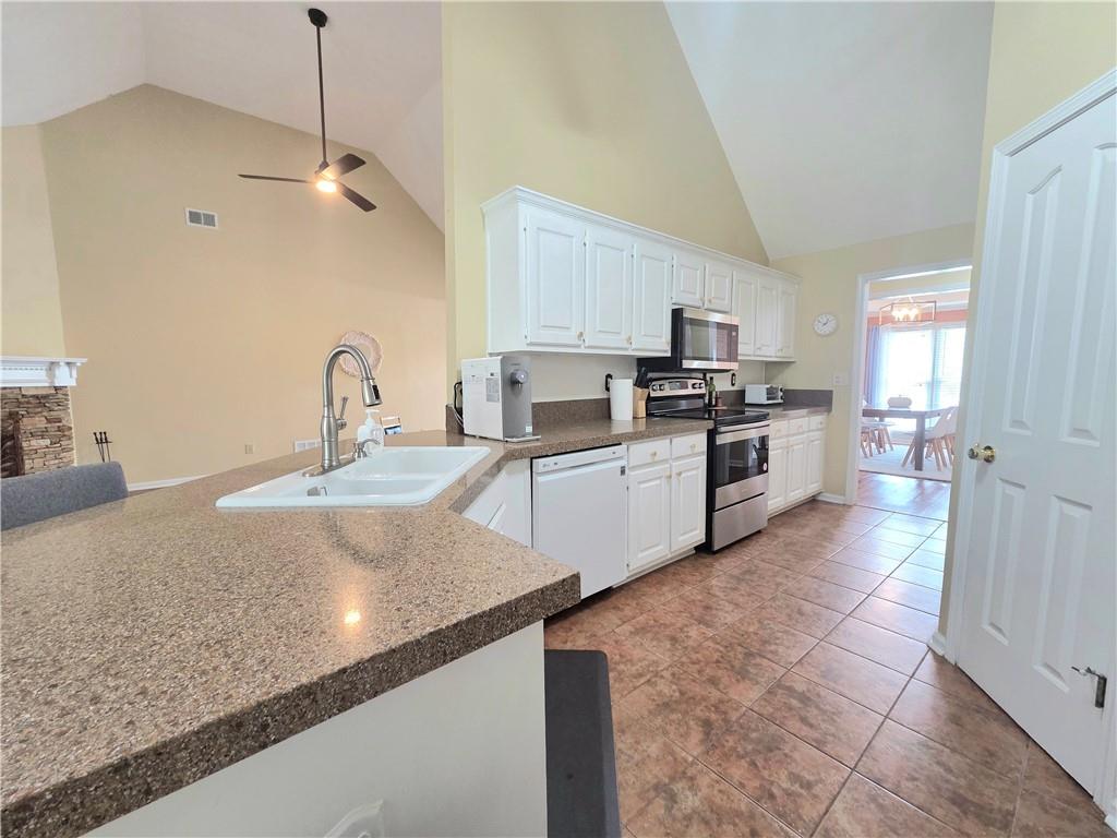 2395 Ashton Ridge Drive Dacula, GA 30019 - Photo 9 of 38 a kitchen with stainless steel appliances granite countertop a sink a stove top oven a counter space and cabinets