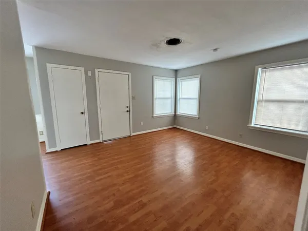 an empty room with wooden floor and windows