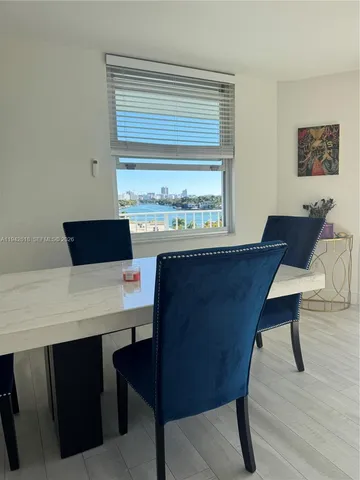 a living room with a table chairs and a refrigerator