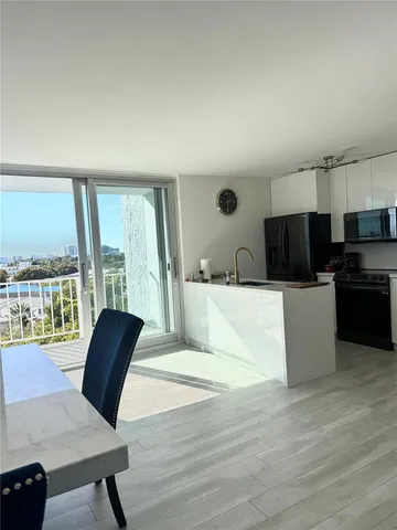 a living room with furniture a large window with kitchen view