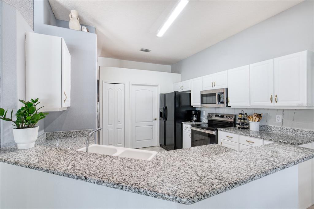 4 Cliffside Drive Ormond Beach, FL 32174 - Photo 29 of 65 a kitchen with stainless steel appliances granite countertop a sink refrigerator stove and microwave