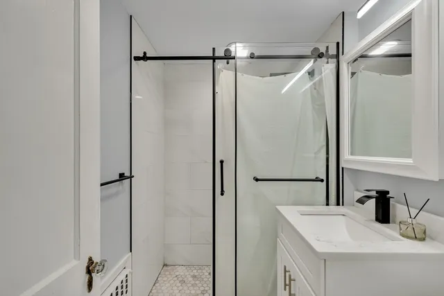 a bathroom with a shower sink vanity and mirror