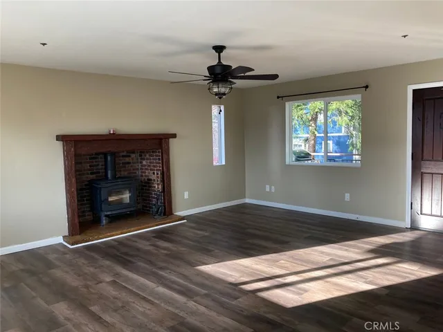 a view of empty room with wooden floor and kitchen