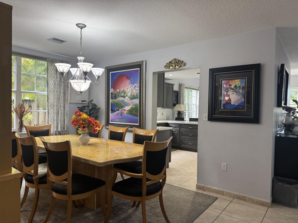 12353 Natalies Cove Road Cooper City, FL 33330 - Photo 10 of 24 a dining room with furniture a flat screen tv and a chandelier