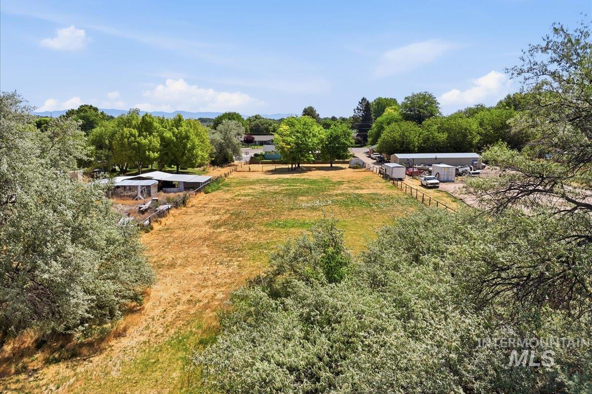 1311 North Middleton Road Nampa, ID 83651 - Photo 12 of 49 Expansive property featuring a large open field, perimeter fencing, mature trees, and a distant mountain backdrop