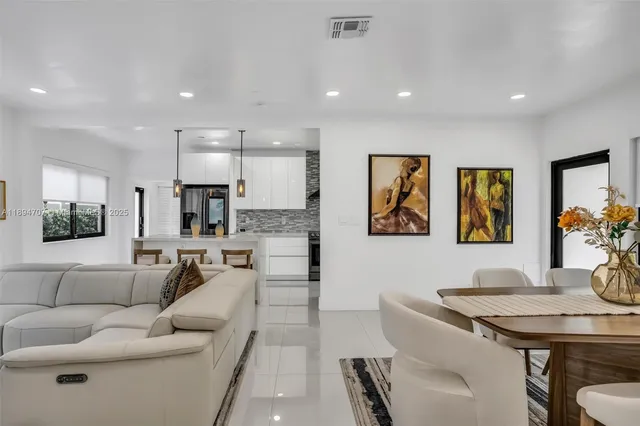 a kitchen with stainless steel appliances kitchen island granite countertop a refrigerator a sink a stove and chairs with wooden floor