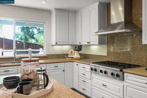 a kitchen with granite countertop a sink a stove and wooden cabinets