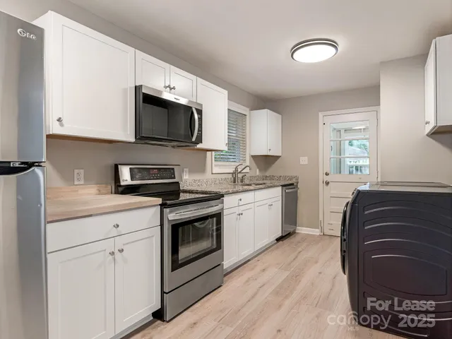 a kitchen with stainless steel appliances granite countertop a stove top oven a sink dishwasher and a microwave oven with cabinets