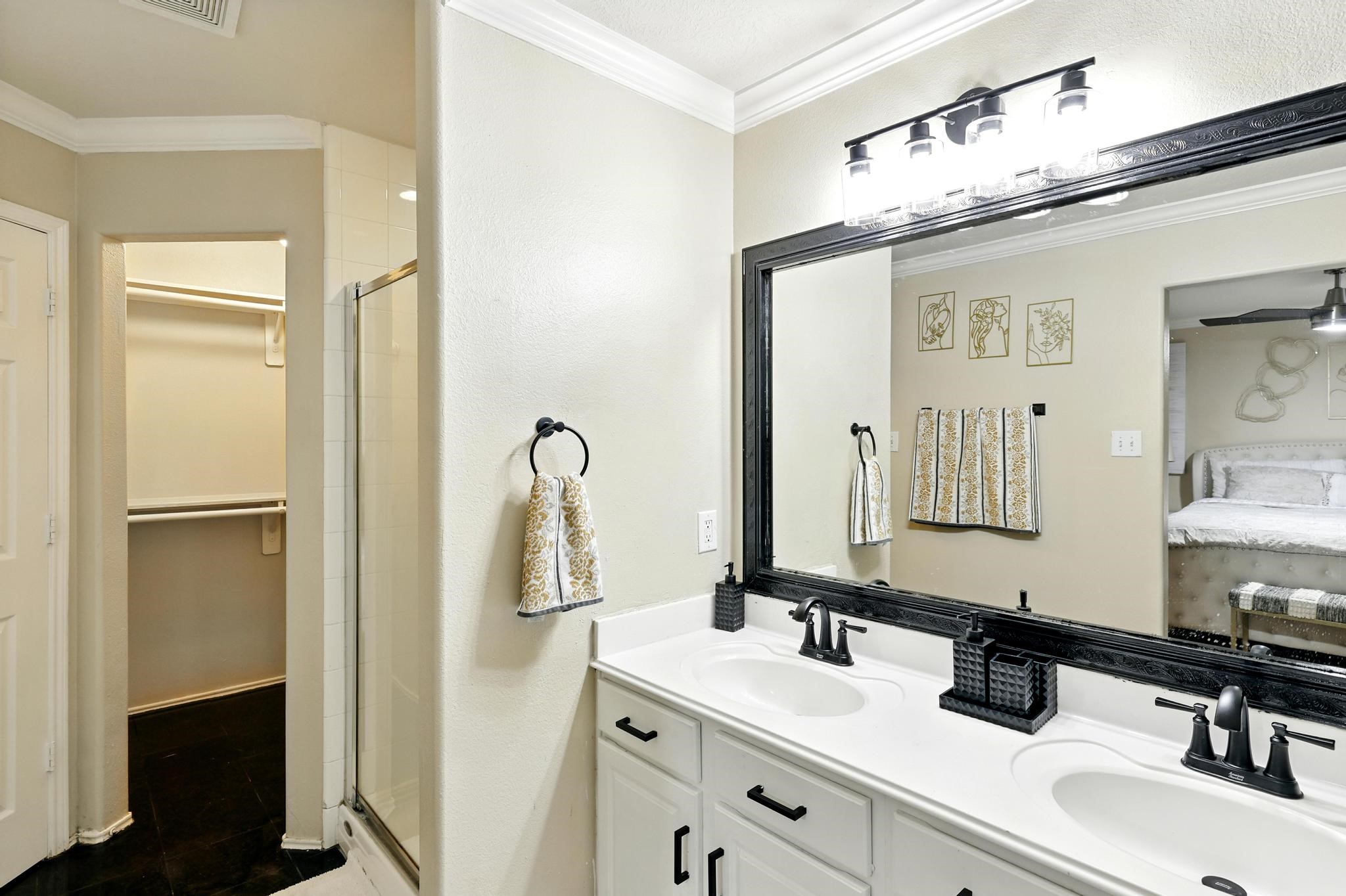 3002 Trinity Pass Court Spring, TX 77373 - Photo 16 of 22 The primary ensuite includes a dual-sink vanity with framed mirror, modern fixtures, a glass-enclosed shower, and a generous walk-in closet.