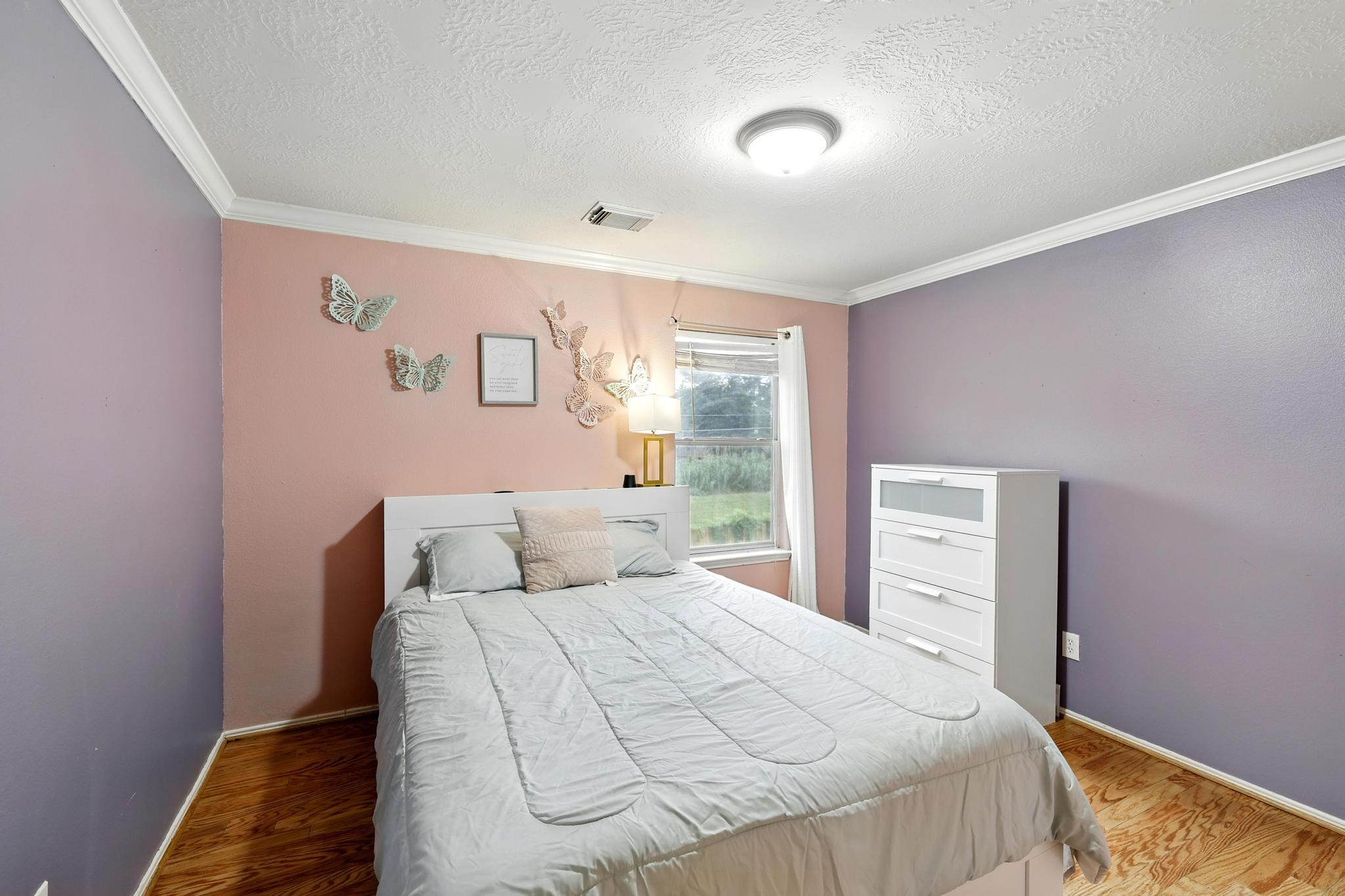 3002 Trinity Pass Court Spring, TX 77373 - Photo 19 of 22 Charming secondary bedroom with crown molding, warm wood flooring, and soft accent walls, offering a cozy and colorful retreat.