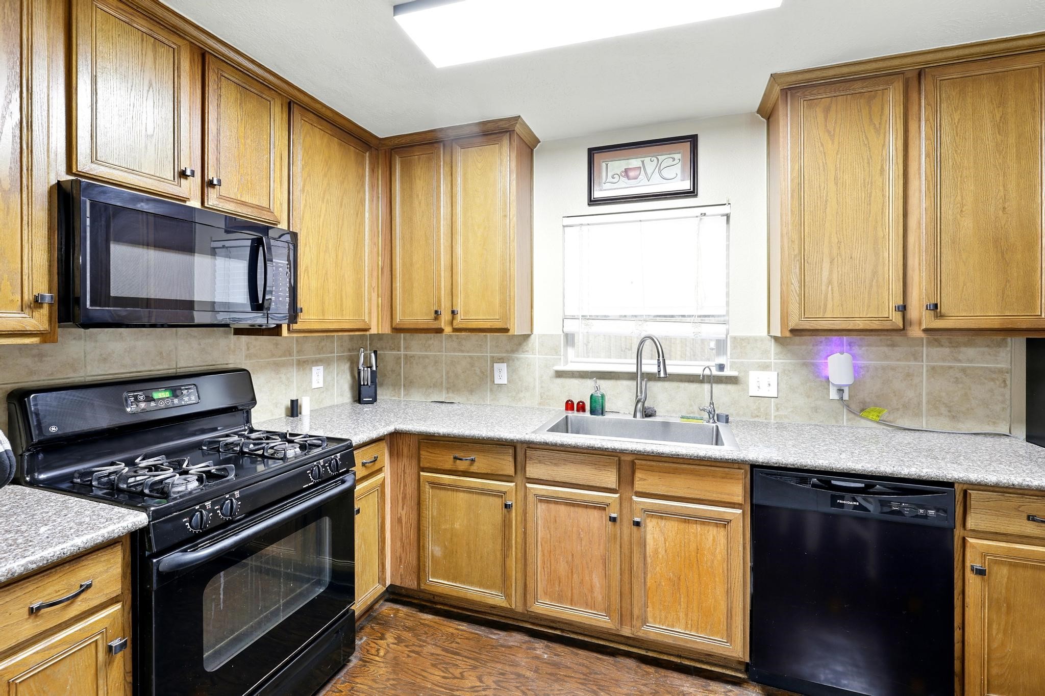 3002 Trinity Pass Court Spring, TX 77373 - Photo 8 of 22 This inviting kitchen offers classic wood cabinetry, durable countertops, and a full suite of appliances including a gas cooktop and dishwasher, blending practicality with warmth.