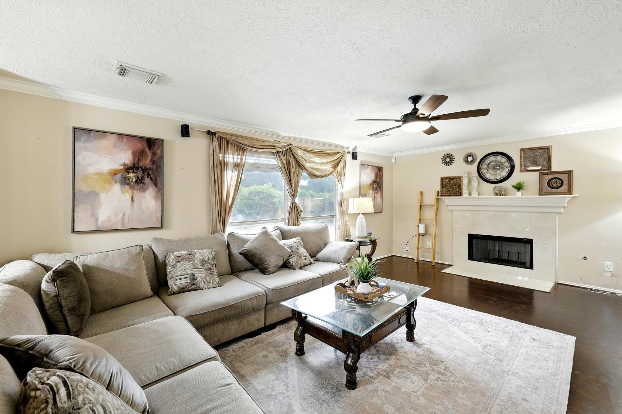 3002 Trinity Pass Court Spring, TX 77373 - Photo 9 of 22 Spacious family room features a classic fireplace, crown molding, and rich wood flooring for a warm and welcoming atmosphere. Large windows provide natural light and backyard views.